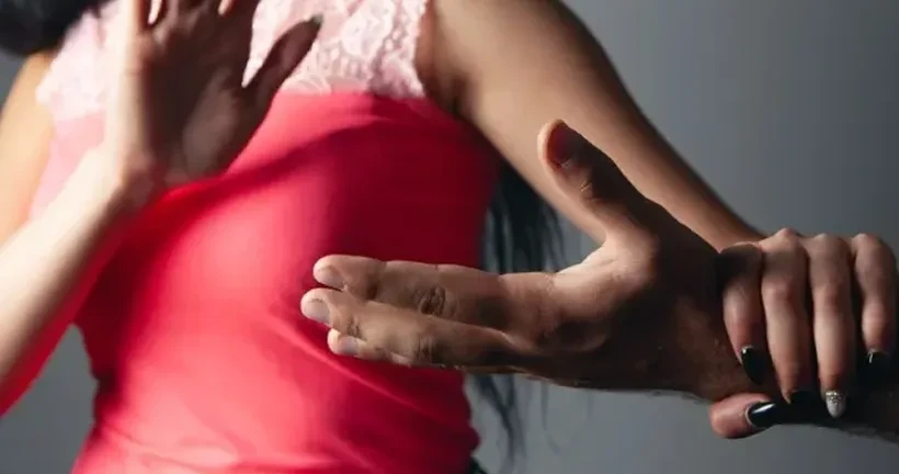 A woman holding up one hand defensively while grabbing and stopping a man's hand.