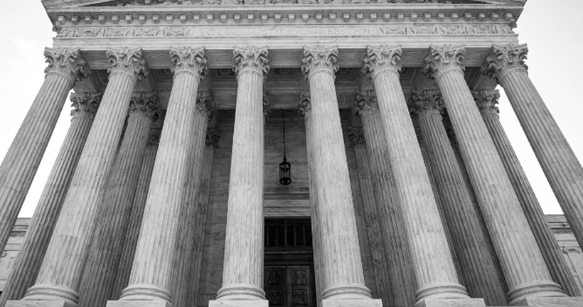 Black and white shot of the grand columns at the entrance of a classical courthouse building.