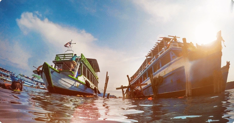 Two large tour boats anchored in the sea on a sunny day, viewed from a low angle at water level.